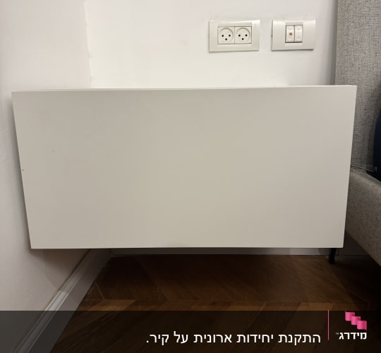 שקעי חשמל על קיר ליד רהיט עץ